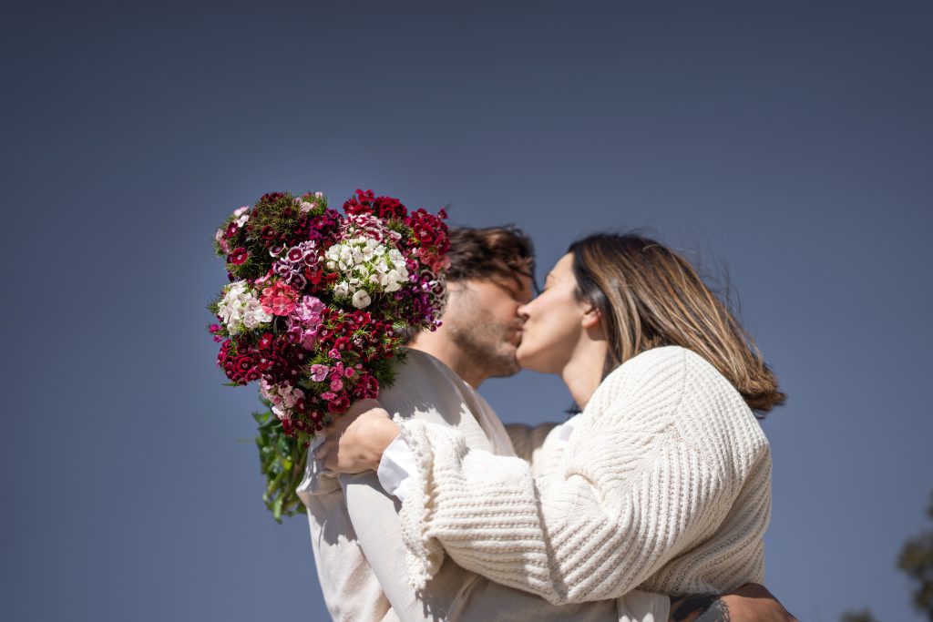 casal-se-beijando-segurando-flores